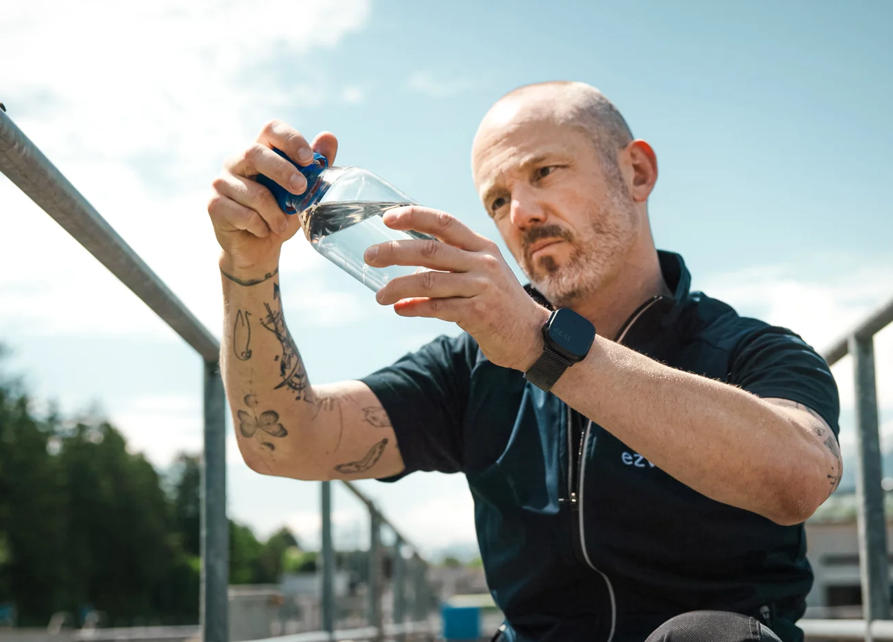 Mitarbeiter der Kläranlage prüft eine Wasserprobe in einem Glasbehälter.